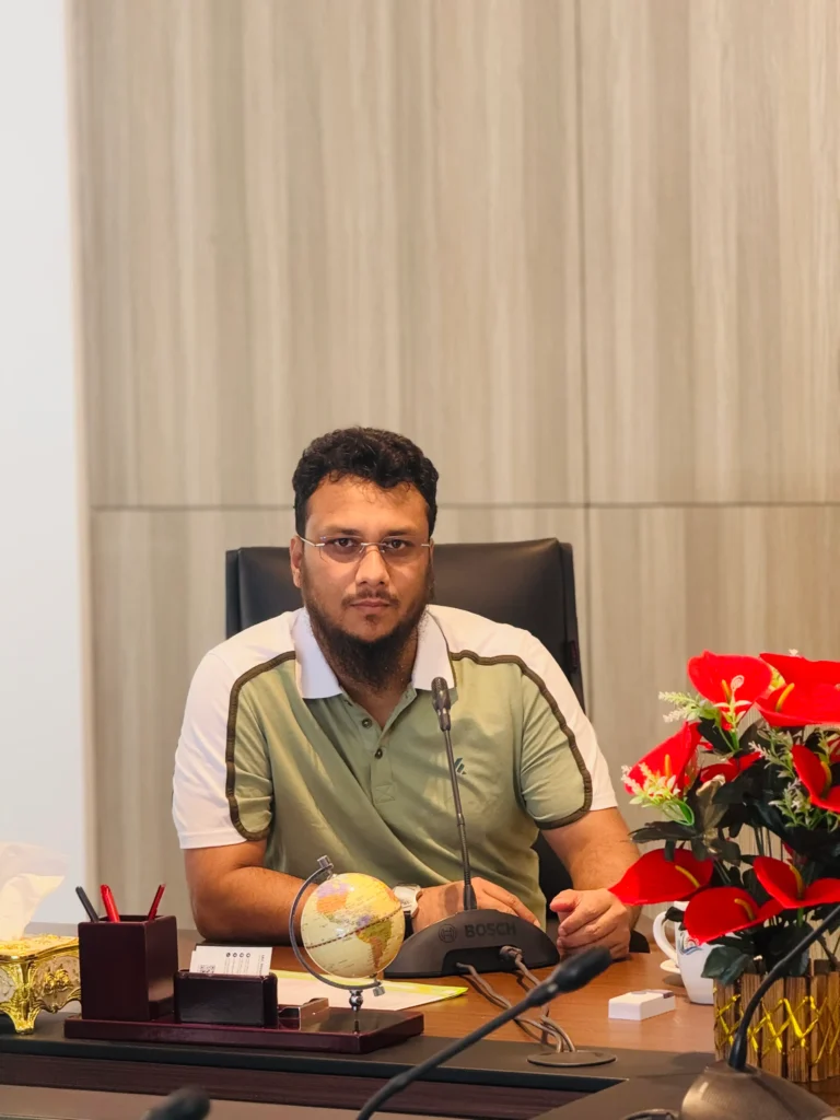 SEO consultant Ataullah Bokhari at desk in an office, focused on organic SEO, AI-driven strategy, and audit work